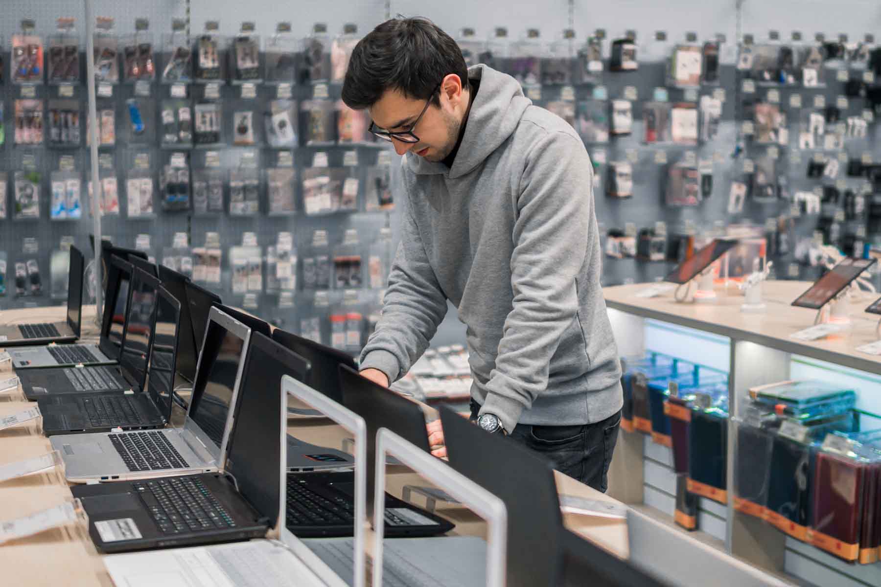 Young man in an electronics store browsing laptop computers