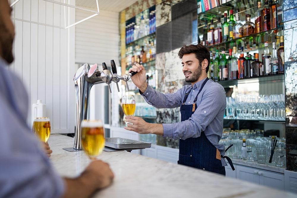 bartender filing beer in a glass from tap