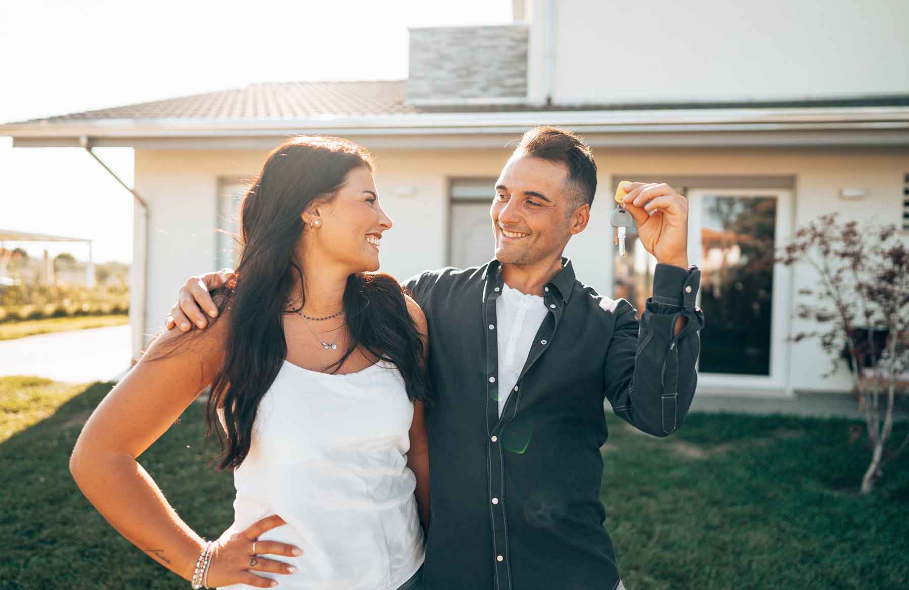 Couple standing in front of new home holding keys