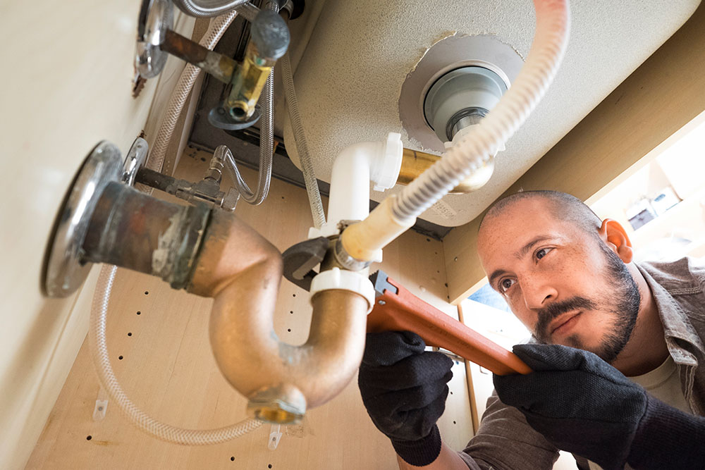 Young male plumber fixing a sink