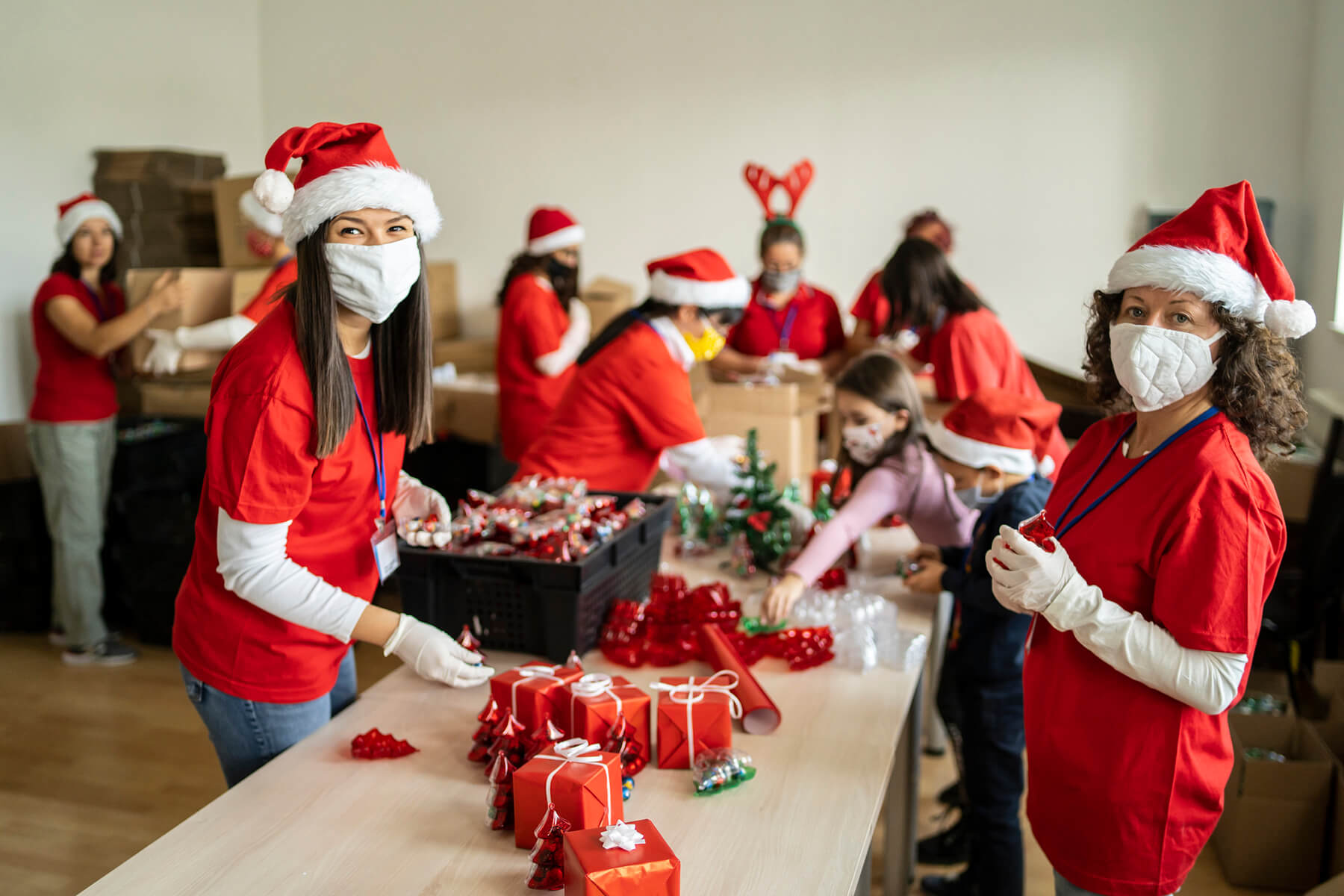 Volunteers with masks wrapping holiday gift donations