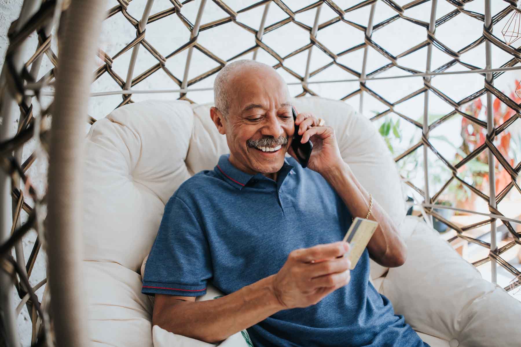 Senior man holding a credit card and talking on the phone.