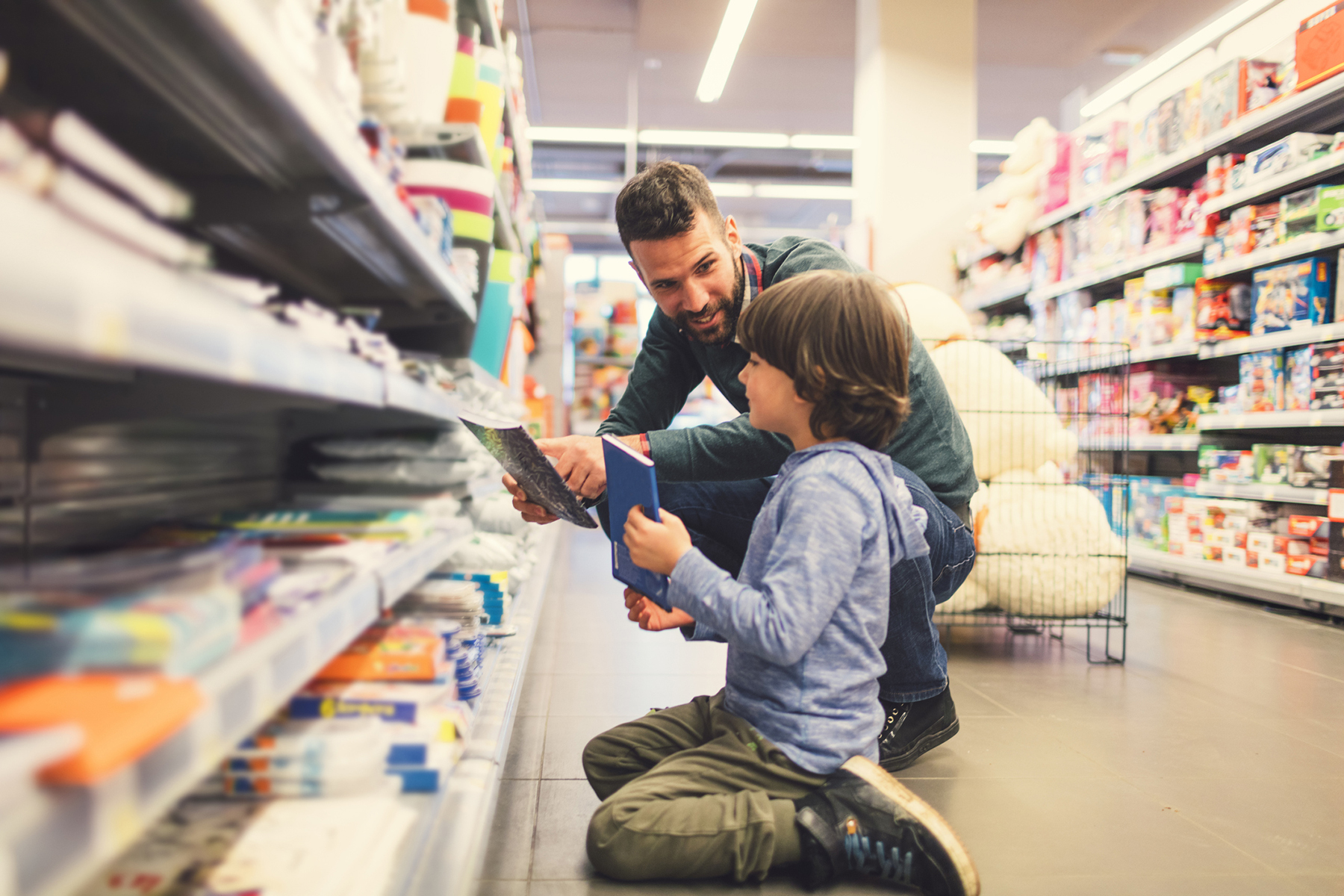 A boy and his father choose notebooks in the stationery aisle.