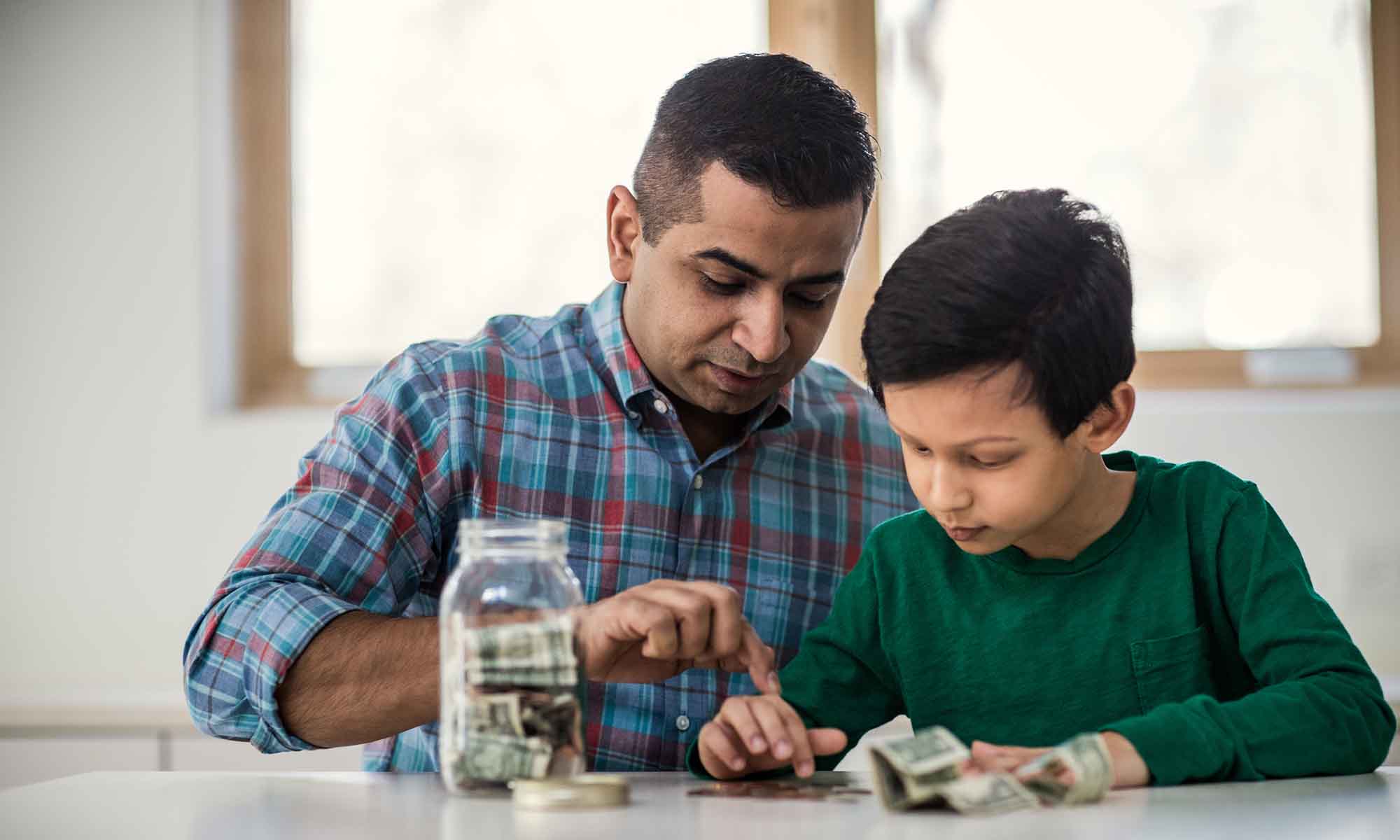Father and son counting money from a savings jar