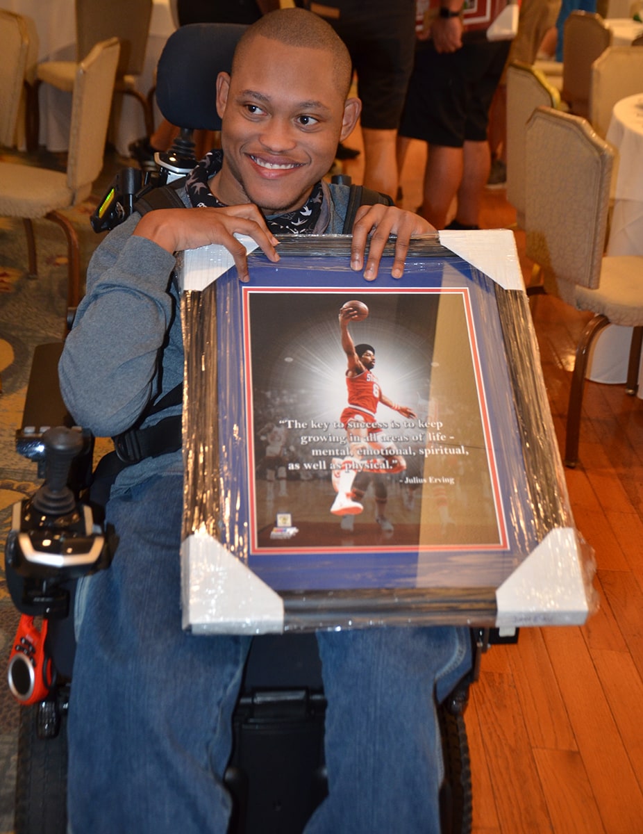 man in wheelchair with framed item from kids n hope Awards Dinner and Silent Auction