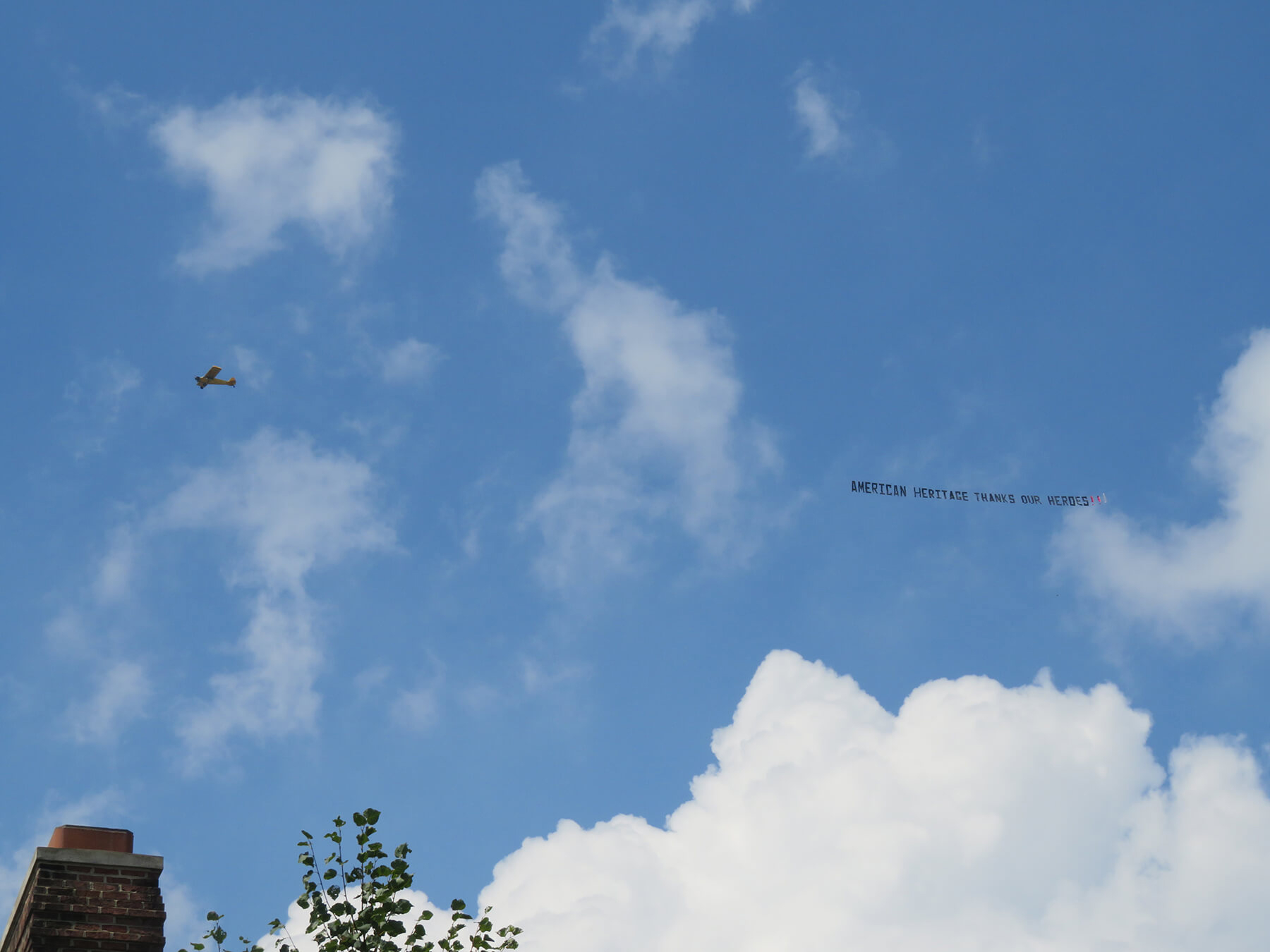 Airplane with banner that says "American Heritage Thanks Our Heroes" flies over American Heritage's campus.