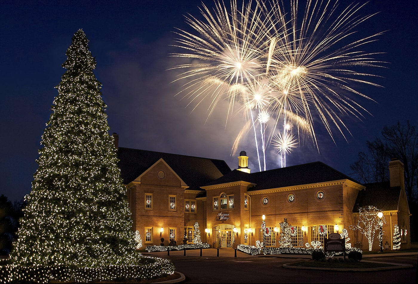 American Heritage Federal Credit Union building at night with fireworks and tree with lights