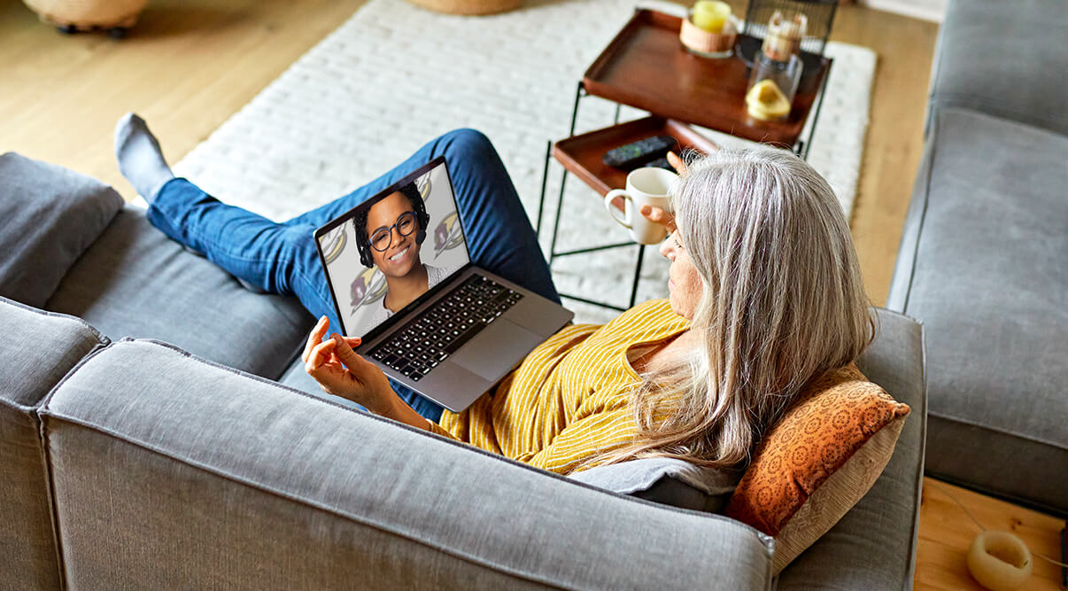Woman laying on a couch with a laptop on her lap using American Heritage's Video Advisor Service