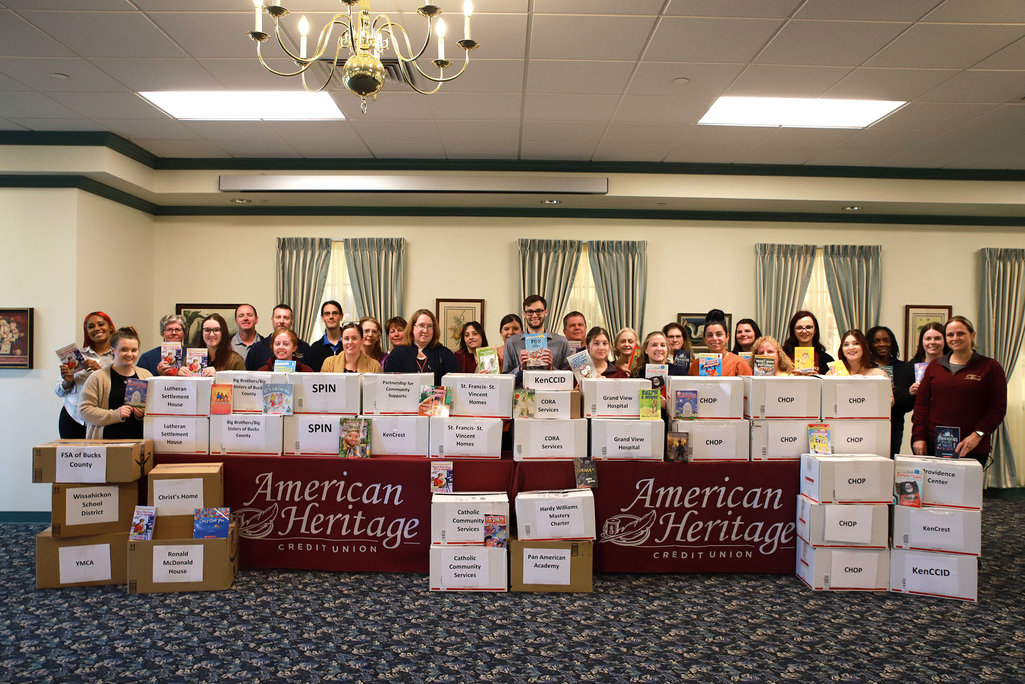 Volunteers stand behind boxes packed wit books to be donated to local pediatric organizations and hospitals.