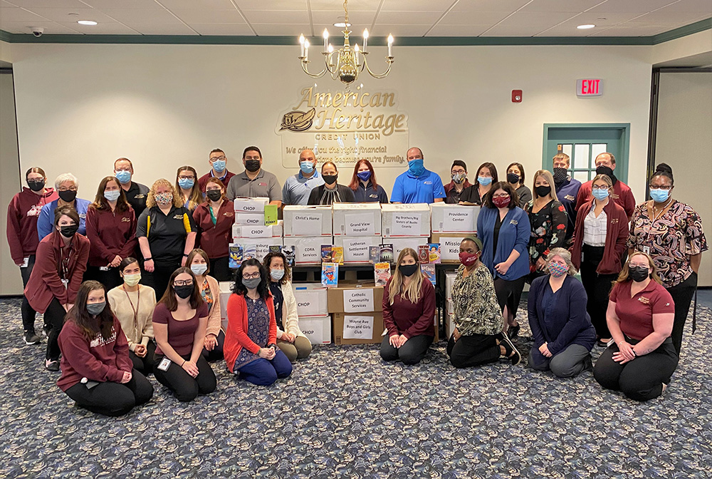 Books for Kids Committee members sit and stand around boxes of book donations