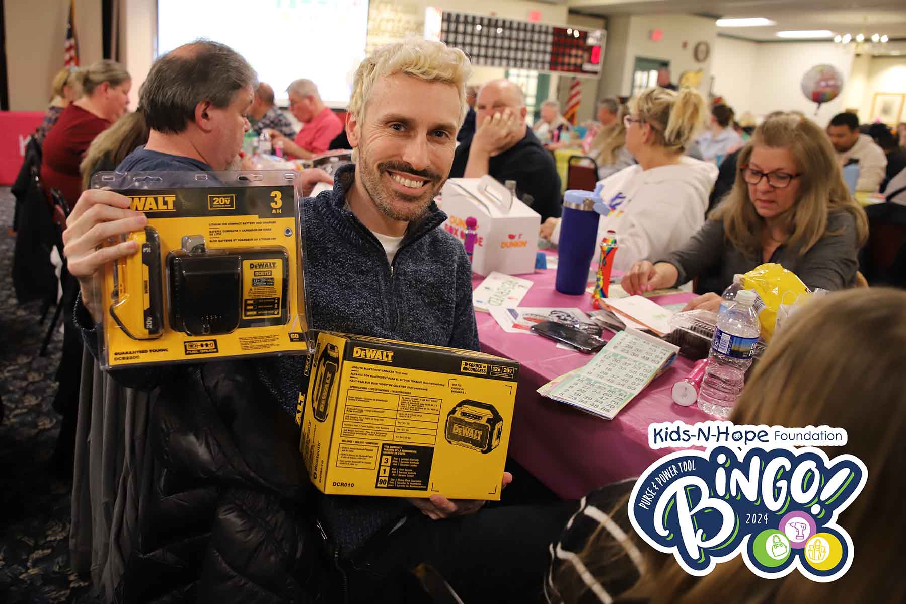 A bingo winner holds up boxes of power tools