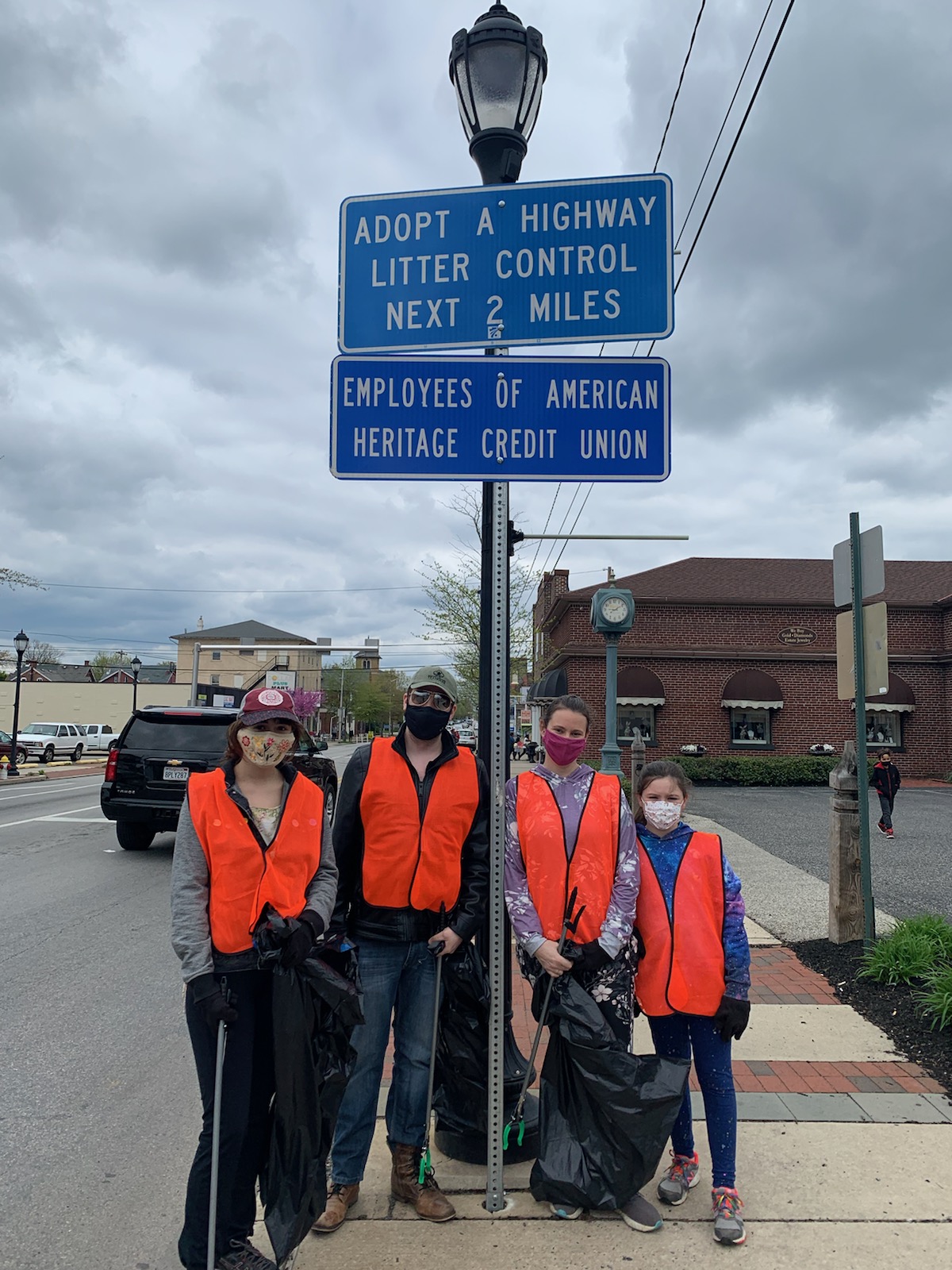 Volunteers stand under an Adopt-A-Highway sign for clean-up event.