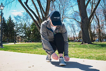 Walk-A-Thon Participant Ties Shoe Along Sidewalk to Prepare for Walk