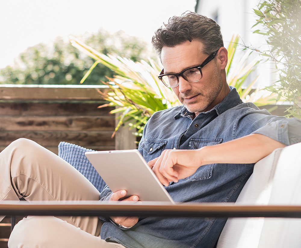 Man sitting outside, reading on a tablet