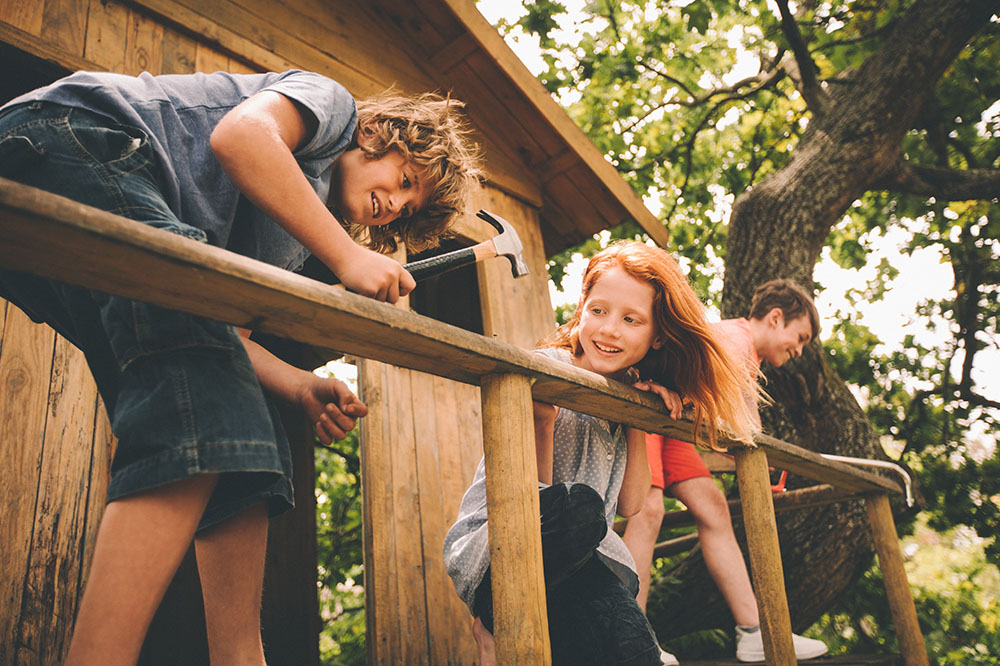 three children building a treehouse.